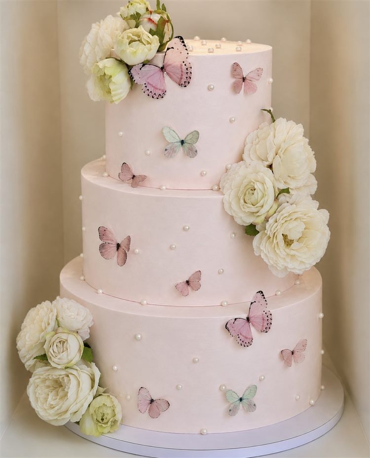 Three-tier blush cake with pearls, butterflies and white roses